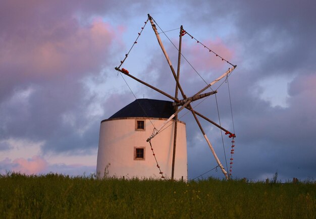 Foto molino de viento tradicional en un campo de hierba contra el cielo durante la puesta de sol