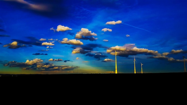 Foto molinos de viento contra el cielo azul durante la puesta de sol