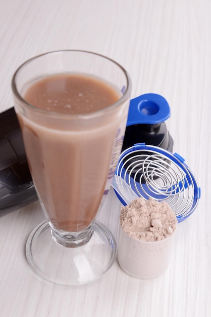 Molkenproteinpulver mit Shake und Plastikshaker auf Holzhintergrund