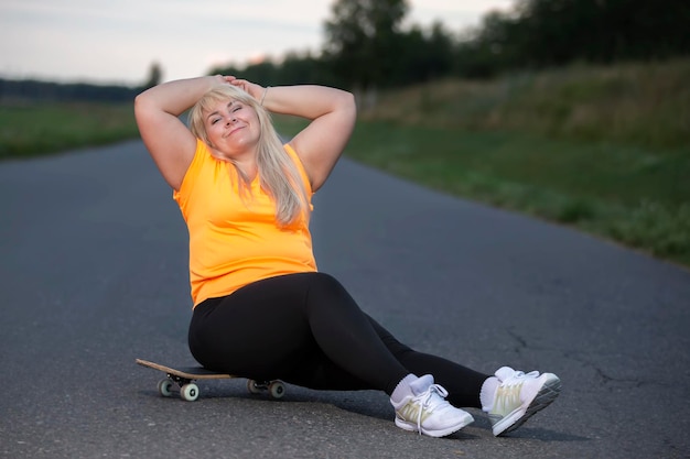 Mollige europäische Frau mittleren Alters mit Übergewicht in einem Trainingsanzug mit Skateboard