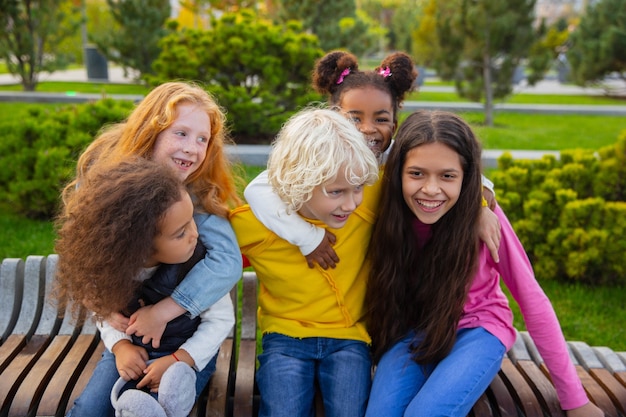 Momente. Interracial-Gruppe von Kindern, Mädchen und Jungen, die am Sommertag im Park zusammen spielen. Freundschaft hat keine Rasse. Glück, Kindheit, Bildung, Diversity-Konzept. Schauen Sie glücklich und aufrichtig.