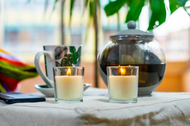 Foto momento acogedor del día con una taza de té caliente velas aromáticas en el fondo de una gran ventana