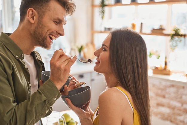 Momento de felicidad. Hombre morena alegre manteniendo una sonrisa en su rostro mientras mira a su pareja