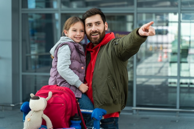 Foto momento feliz a visão do retrato da cintura para cima do pai está abraçando sua filhinha e expressando alegria enquanto aponta para algo criança alegre se sentindo feliz enquanto espera no aeroporto com o papai