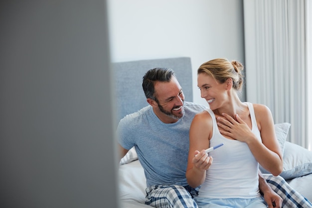 Este momento finalmente está ocurriendo Captura recortada de una pareja de mediana edad que parece feliz después de hacerse una prueba de embarazo casera en su habitación