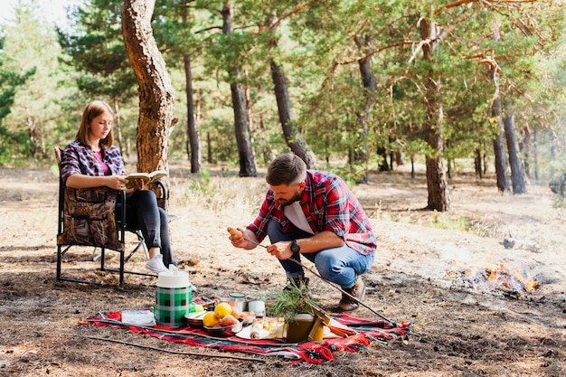 Momento de pareja mientras acampa y prepara comida