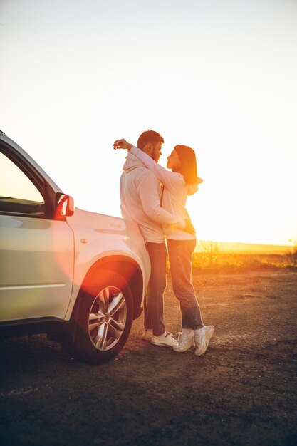 Foto momento romântico casal beijando no pôr do sol perto de carro suv branco