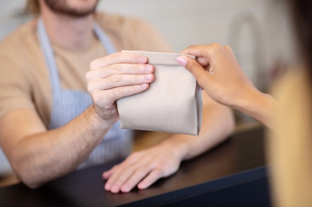 Momento de transferencia. Manos masculinas y femeninas sosteniendo una pequeña bolsa de papel sobre el mostrador en el momento de la transferencia, sin caras