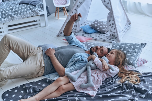 Momentos de amor y felicidad. Padre joven y su pequeña hija tomando selfie