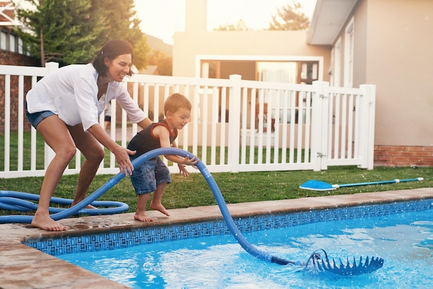 Momentos divertidos junto a la piscina Toma de una madre y su hijo limpiando la piscina juntos