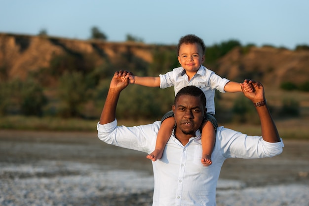 Momentos dulces del concepto de paternidad. Hombre afroamericano emocionado dando caballito a feliz