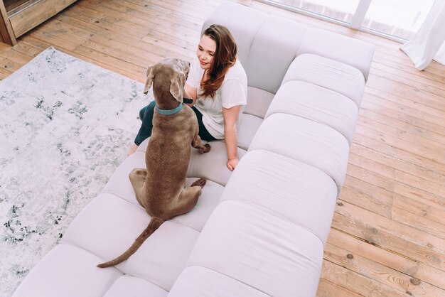 Momentos de estilo de vida de una mujer joven en casa. Mujer jugando con su perro en la sala de estar