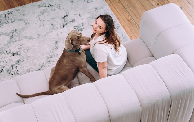 Momentos de estilo de vida de una mujer joven en casa. Mujer jugando con su perro en la sala de estar