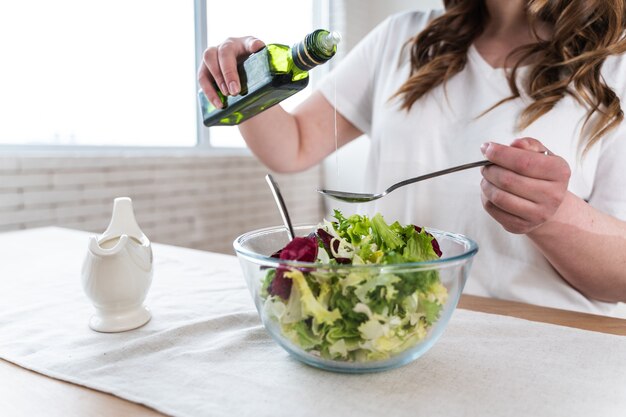 Momentos de estilo de vida de una mujer joven en casa. Mujer preparando una ensalada en la cocina