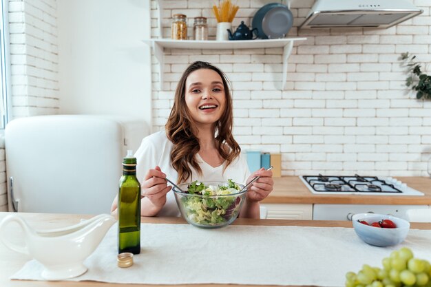 Momentos de estilo de vida de una mujer joven en casa. Mujer preparando una ensalada en la cocina