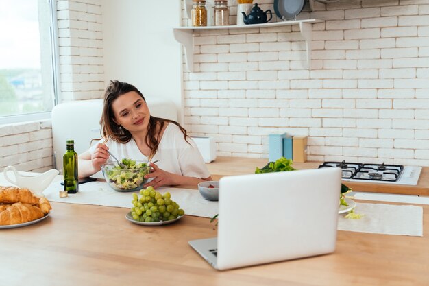 Momentos de estilo de vida de una mujer joven en casa. Mujer preparando una ensalada en la cocina