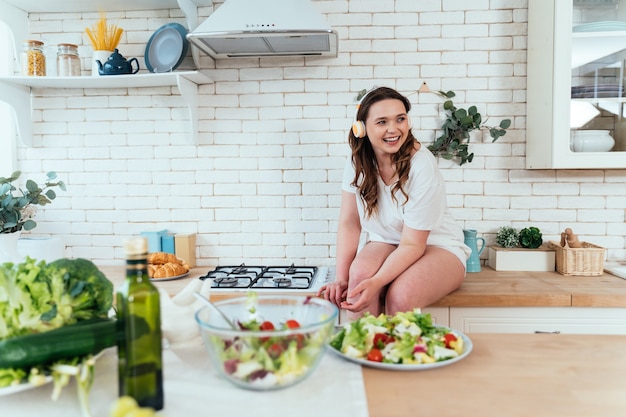 Momentos de estilo de vida de una mujer joven en casa. Mujer preparando una ensalada en la cocina