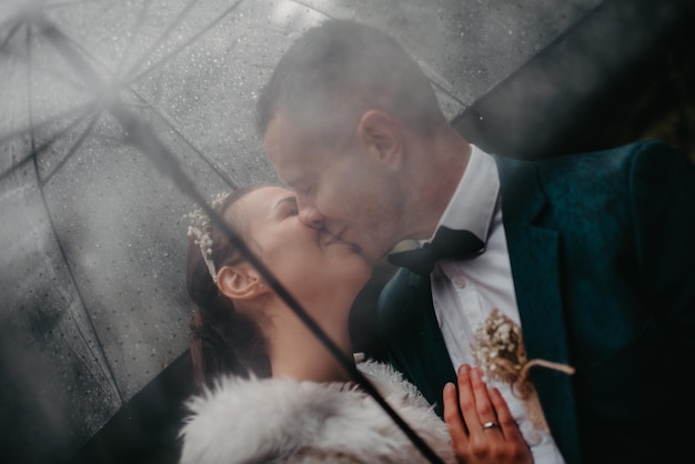 Momentos felices de la boda. Una feliz pareja joven, recién casados caminando por las calles cuando llueve mientras lleva un paraguas. foto de alta calidad