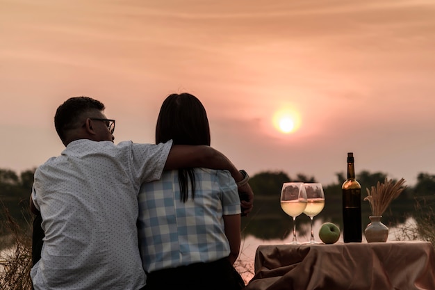 Momentos felices de la vida. Pareja disfrutando de la puesta de sol mientras toma una copa de vino