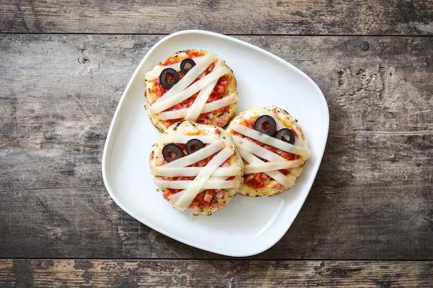 Momias de Halloween mini pizzas en mesa de madera