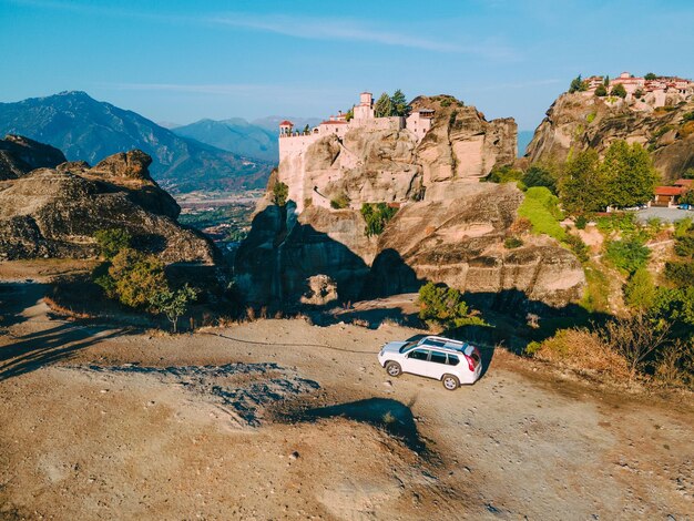 Monasterio de meteora de concepto de viaje por carretera de coche suv en el fondo