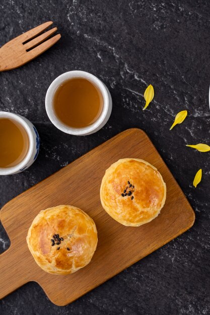 Mondkuchen-Eigelbgebäck, Mondkuchen für Mittherbstfestfest, Draufsichtentwurfskonzept auf dunklem Holztisch mit Kopienraum, flache Lage, Überkopfaufnahme