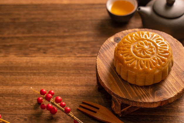 Mondkuchen Mooncake Tischdekoration - Rundes chinesisches traditionelles Gebäck mit Teetassen auf Holzhintergrund, Mid-Autumn Festival-Konzept, Nahaufnahme,