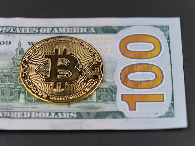 Moneda Bitcoin y billete de 100 dólares estadounidenses