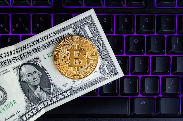 Moneda Bitcoin con laptop y dólares estadounidenses. Bitcoin monedas de oro en un móvil de portátil negro de fondo de oficina de billetes de dólar.