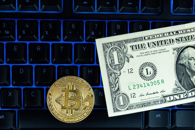 Moneda Bitcoin con laptop y dólares estadounidenses. Bitcoin monedas de oro en un móvil de portátil negro de fondo de oficina de billetes de dólar.
