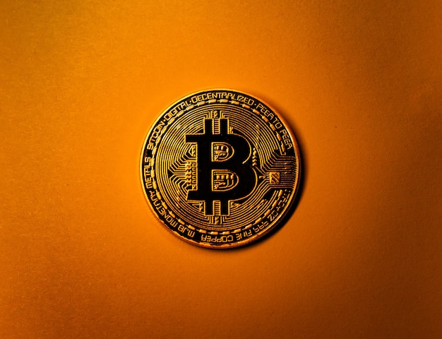 Moneda bitcoin de oro sobre fondo monocromo amarillo