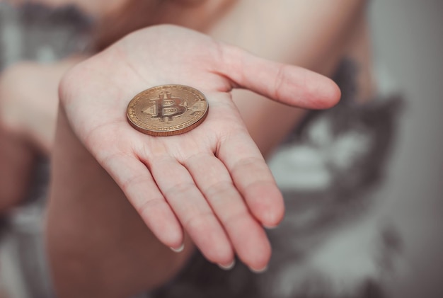 Moneda Bitcoin en una palma femenina