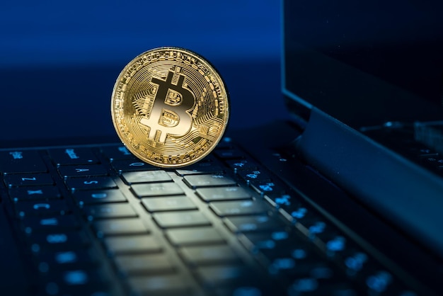 Moneda Bitcoin de pie en el teclado de la computadora