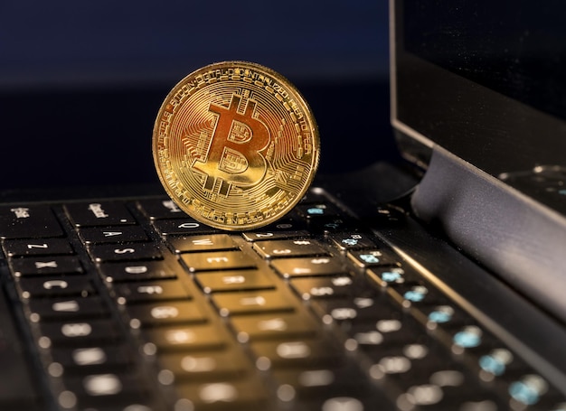 Moneda Bitcoin de pie en el teclado de la computadora