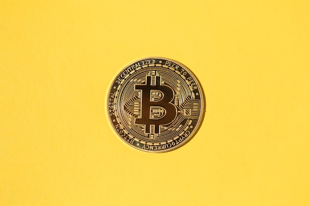 Una moneda Bitcoin sobre fondo amarillo. Concepto de criptomoneda, ahorro de dinero y ahorros.