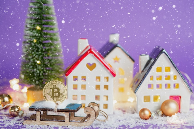 Moneda Bitcoin en trineo de madera pasando casas con luces de colores y nieve, árbol de Navidad. Fondo violeta muy peri. Tarjeta de felicitación de año nuevo. Criptomoneda, finanzas, riqueza e inversión.