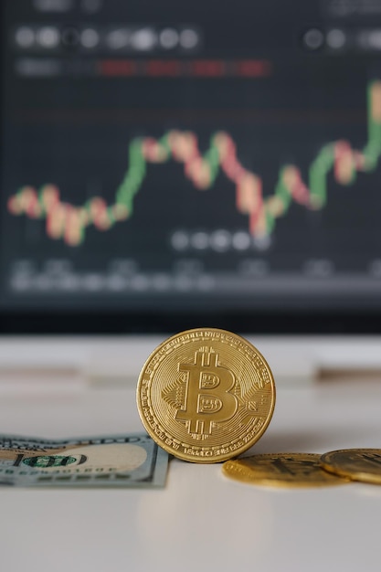 Moneda criptográfica de bitcoin de oro y dólares estadounidenses en el fondo de la tableta con inversión en el diagrama de acciones