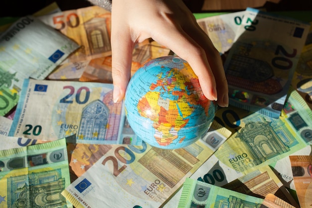 Moneda euro de la Unión Europea y globo modelo en mano Antecedentes financieros