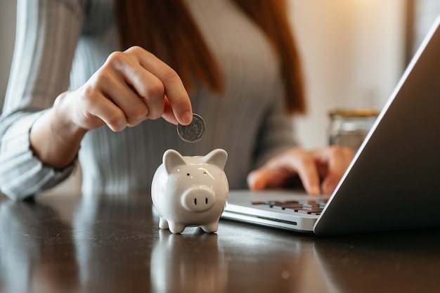 Moneda de explotación de mano de mujer con hucha de cerdo. Concepto de ahorro y cuentas financieras