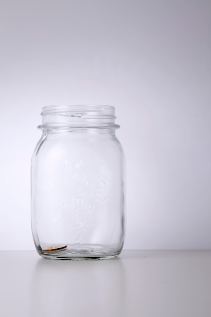 Foto moneda en frasco en la mesa contra un fondo blanco