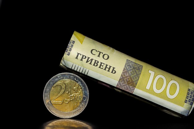 Una moneda hryvnia ucraniana se encuentra en los billetes de cien euros dispersos