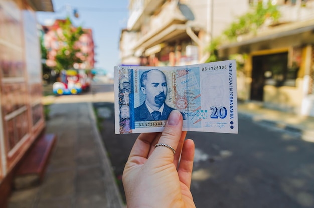 Moneda lev búlgaro La mano de una mujer sostiene un billete de 20 denominaciones en la calle Pago de bienes y servicios