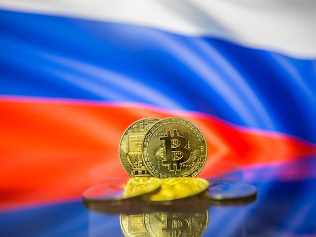 Moneda de oro Bitcoin y bandera desenfocada de fondo de Rusia. Concepto de criptomoneda virtual.