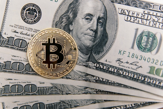 Moneda de oro de Bitcoin en billetes de cien dólares estadounidenses. Concepto de negocio de criptomonedas. Cambie bitcoin cash por un dólar. Inversión virtual de dinero.