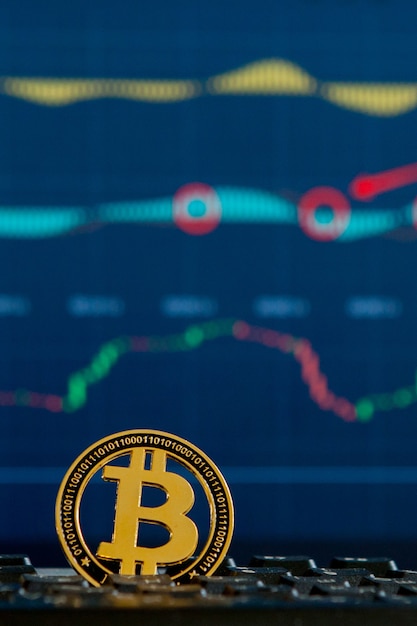 Moneda de oro Bitcoin y fondo gráfico desenfocado