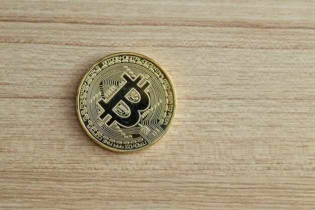 Moneda de oro Bitcoin sobre fondo de madera