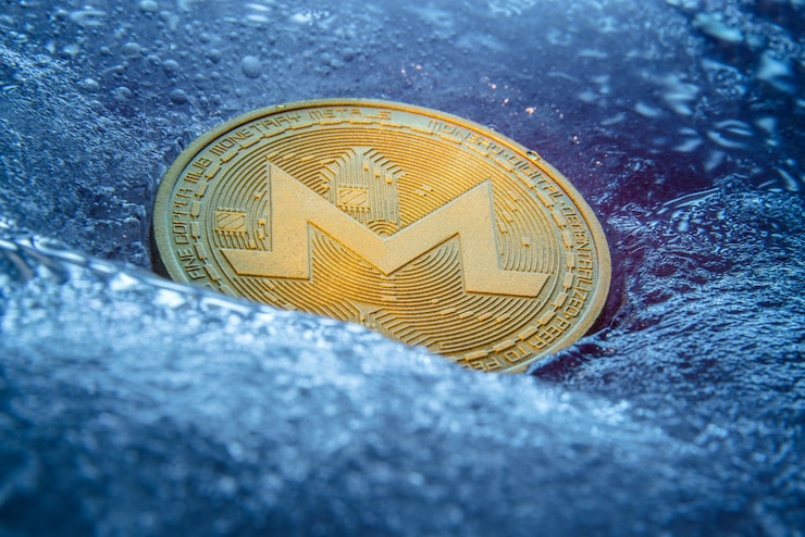Foto moneda de oro monero, moneda digital en línea congelada en el hielo azul.