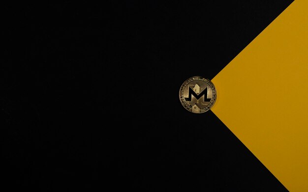 Moneda de oro Monero sobre fondo negro y amarillo como criptomoneda de sobre y criptoinversión