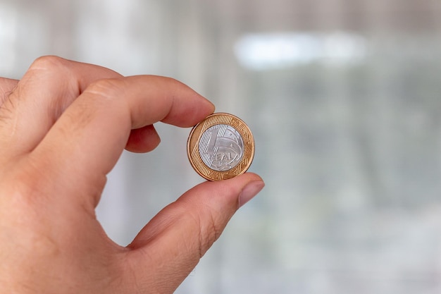 Una moneda real en la palma de la mano de una persona Mano sosteniendo una moneda de 1 dólar El real es el sistema monetario del gobierno brasileño