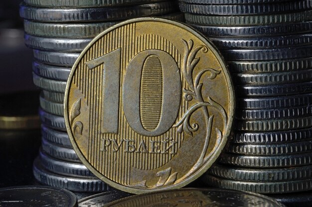 Moneda rusa en denominación de 10 rublos (reverso) contra el fondo de otras monedas dobladas en columnas.